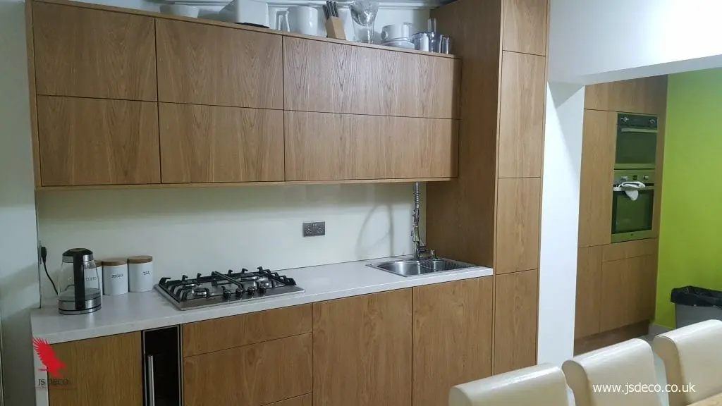 Modern oak veneered handleless kitchen in Wakefield with hob, sink, wall units, and tall housing