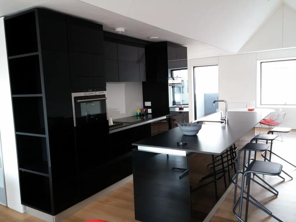 Black high gloss kitchen furniture with island and tall cabinets in Manchester