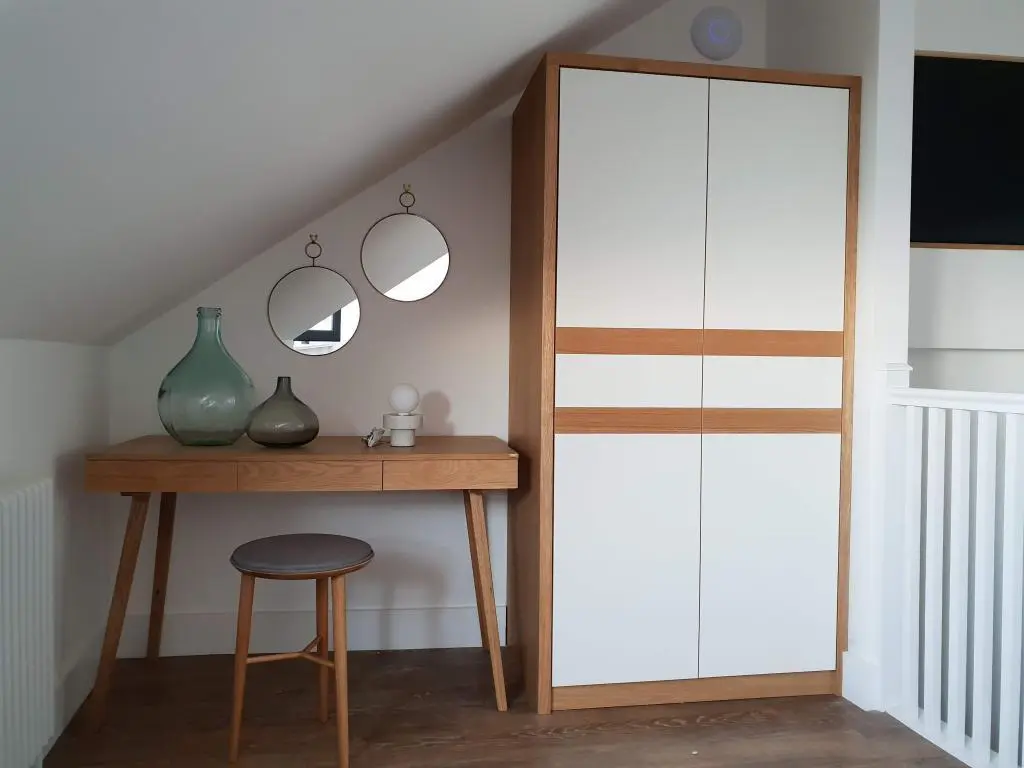 Fitted wardrobe in St Ives Cornwall guest house bedroom with white doors, natural oak inlays and push to open handle less design