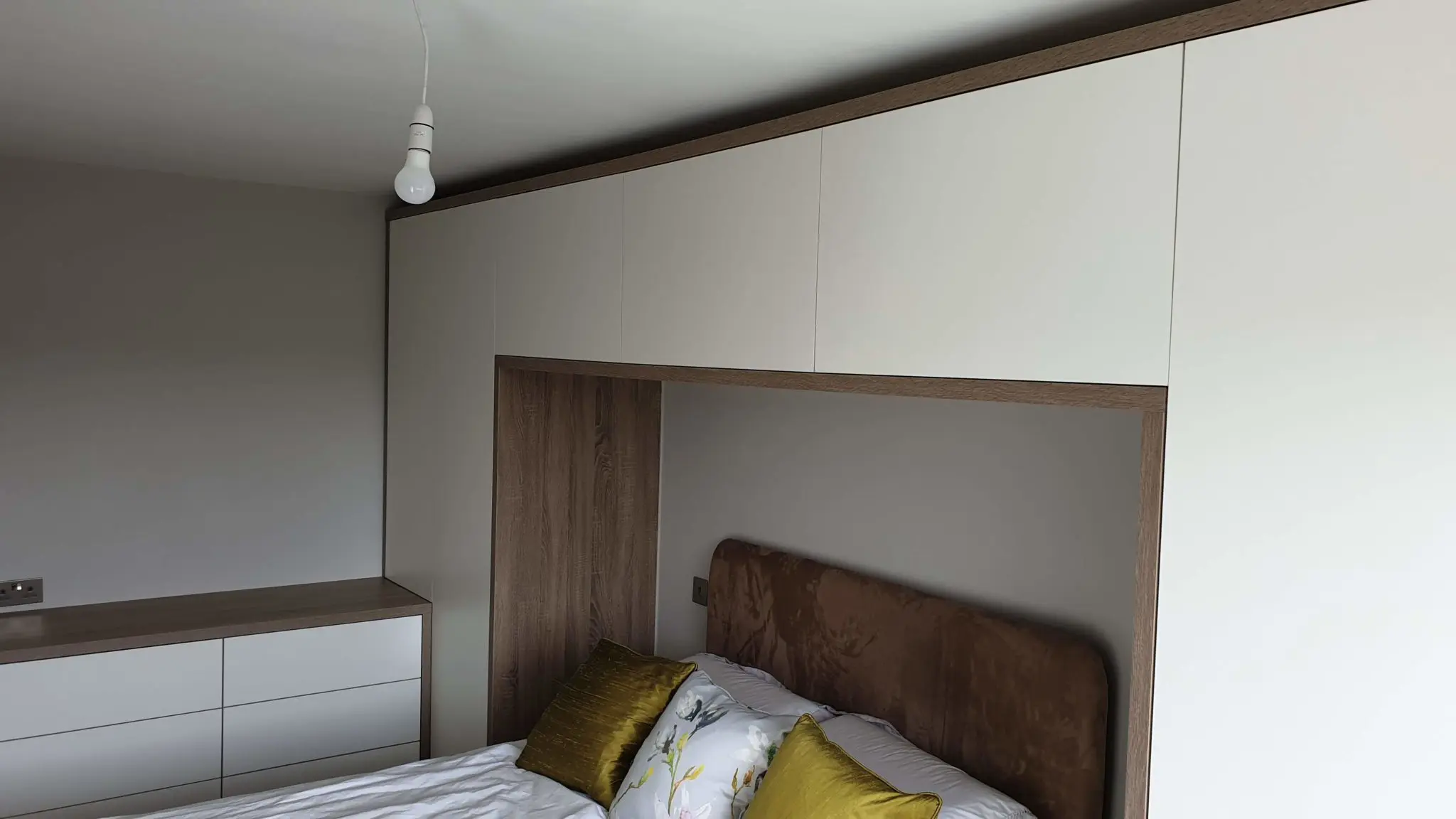 Fitted bedroom wardrobes with oak-framed bridging unit installed in a Silkstone home