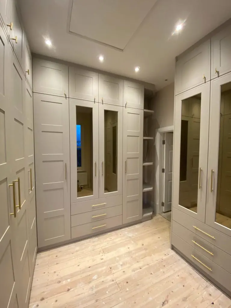 Walk-in wardrobe with mirrored doors, lower drawers and a separate upper cupboard tier