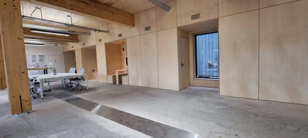 Plywood panels coordinate architectural openings and the long office elevation.