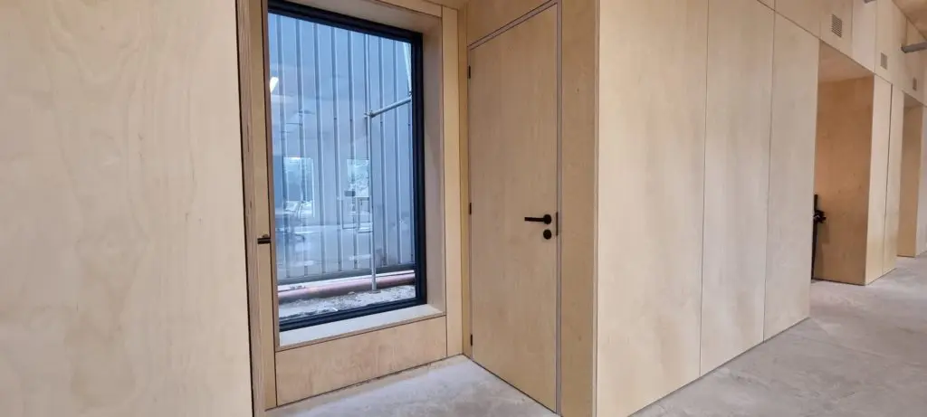 Internal doors incorporated into the plywood wall treatment.