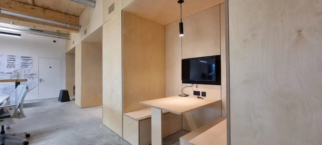 A recessed workstation with an integrated screen, framed by birch plywood.