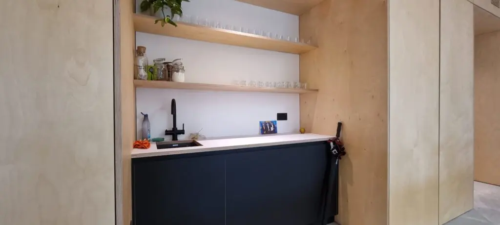 An office kitchenette with a contrasting finish and plywood surroundings.