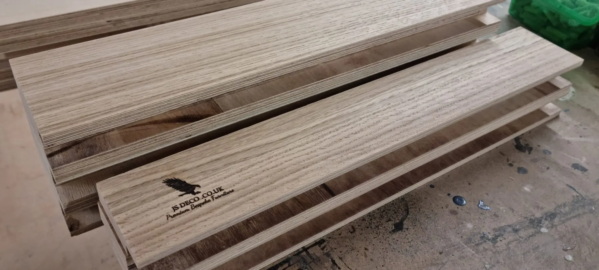 Close-up of solid oak joinery detail with JS DECO branding on a fitted wardrobe drawer during manufacture.
