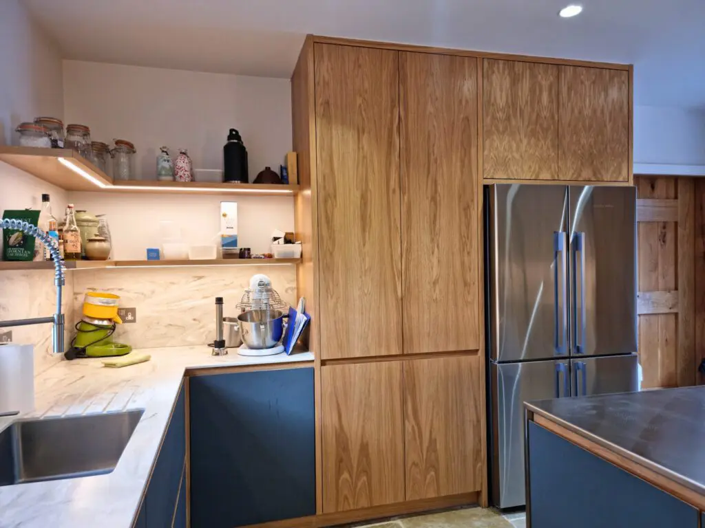 Tall oak cabinetry arranged around the American-style fridge freezer