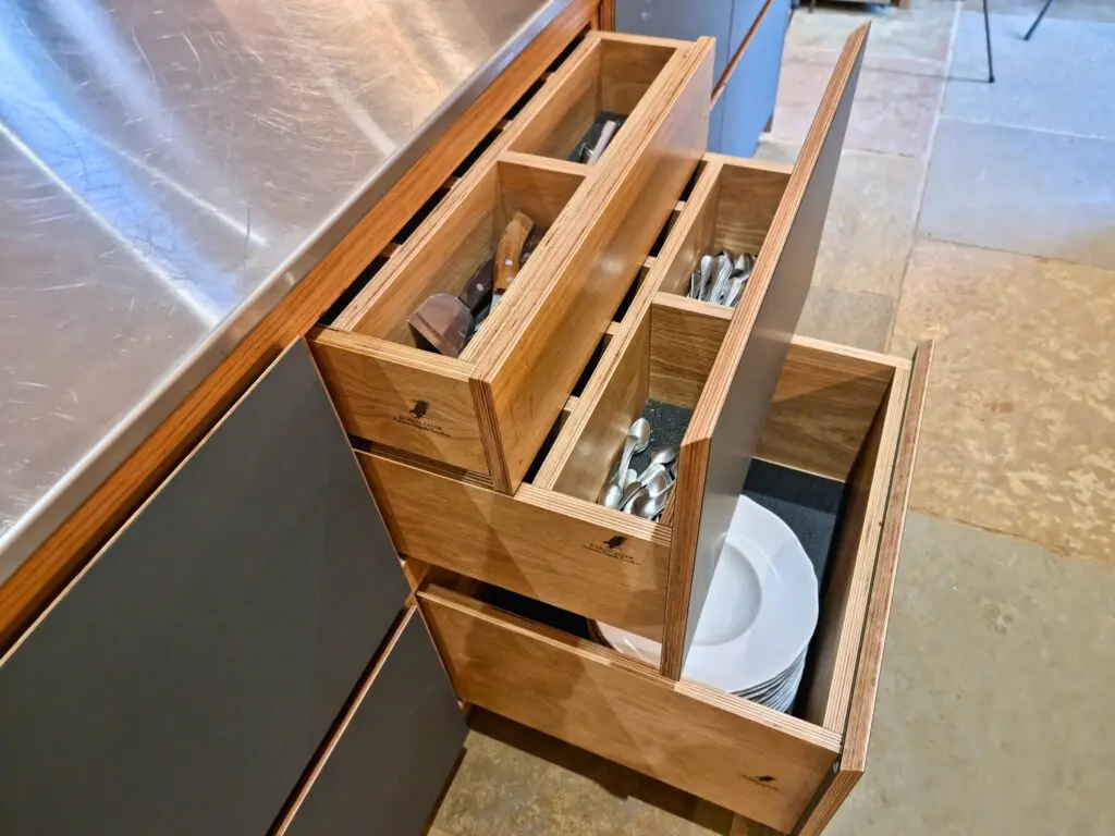 Divided oak drawers organise utensils above deeper storage