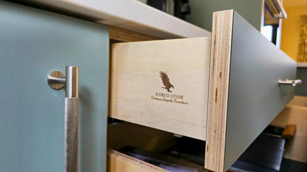 The open plywood drawer reveals its layered front edge and JS DECO workshop mark.