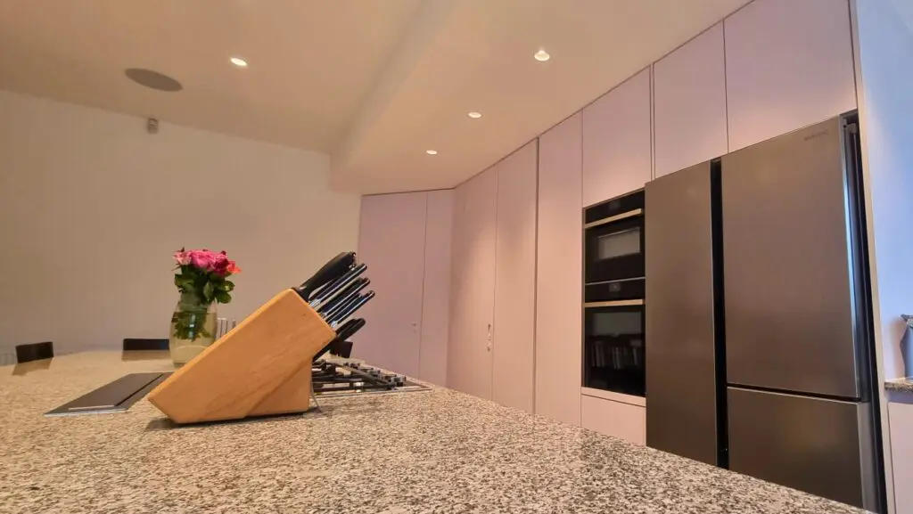 The island hob and granite worktop alongside the tall appliance cabinetry.