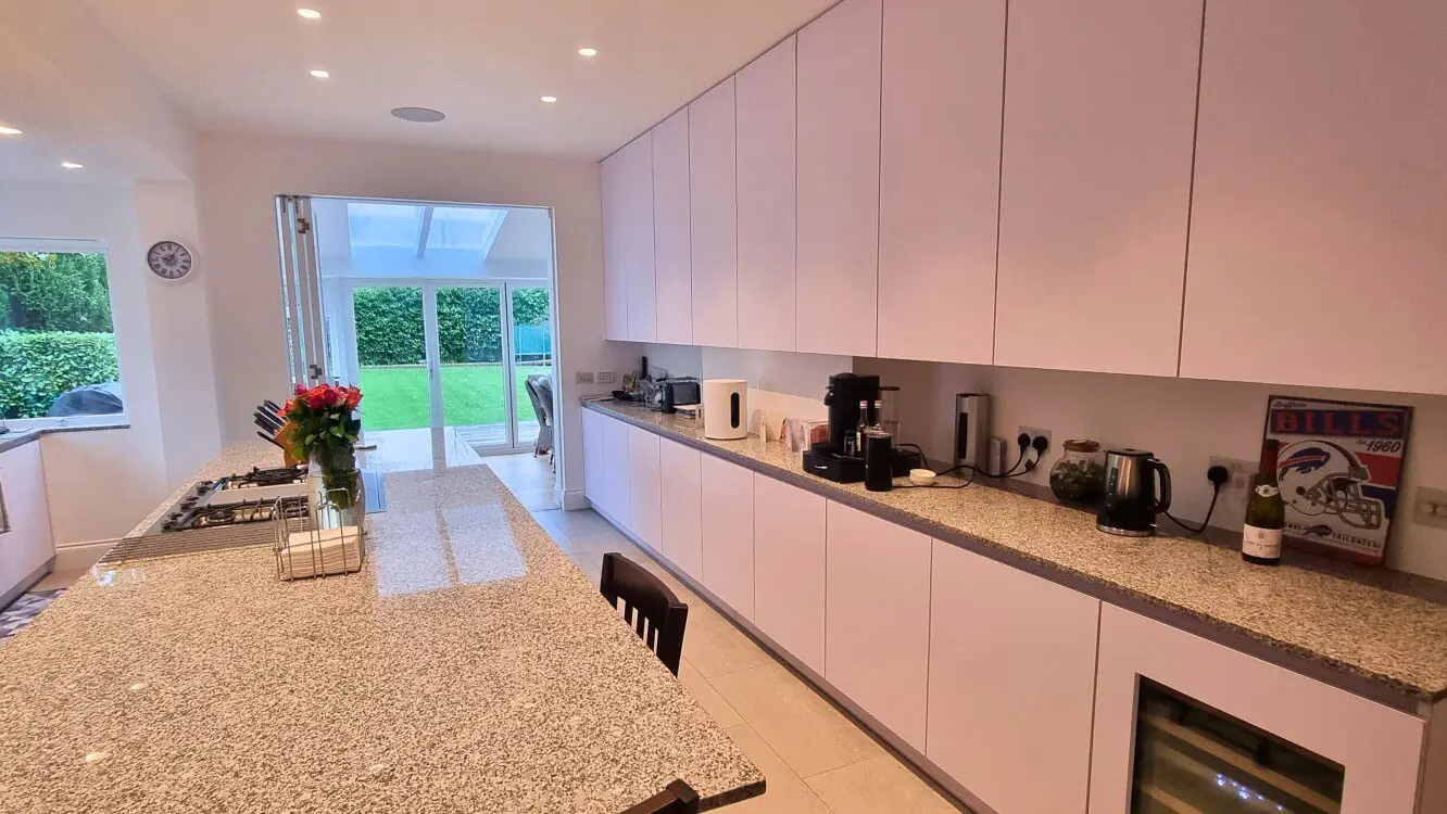 White FENIX kitchen with long worktop and open-plan layout White FENIX kitchen with bespoke long worktop and open-plan layout