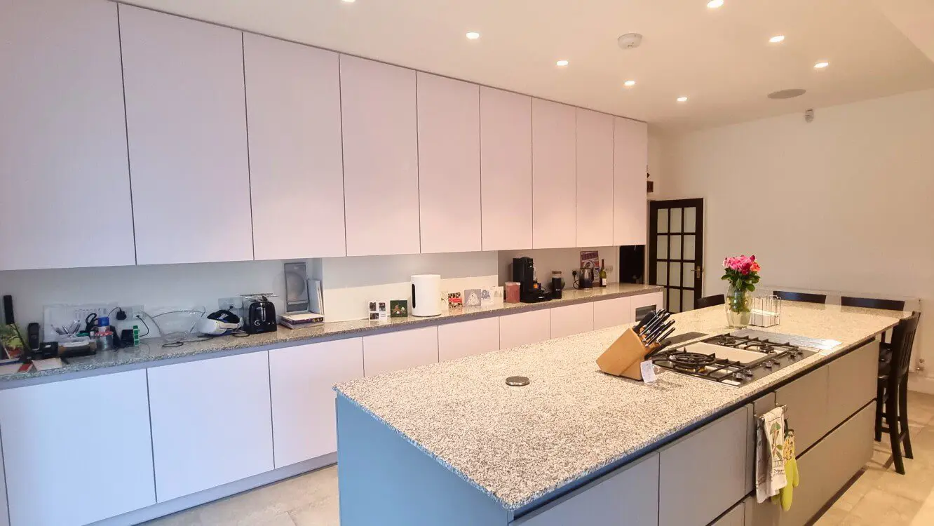 White FENIX kitchen with full-height cabinets and grey island White FENIX kitchen with full-height cabinets and a large grey island with granite worktop