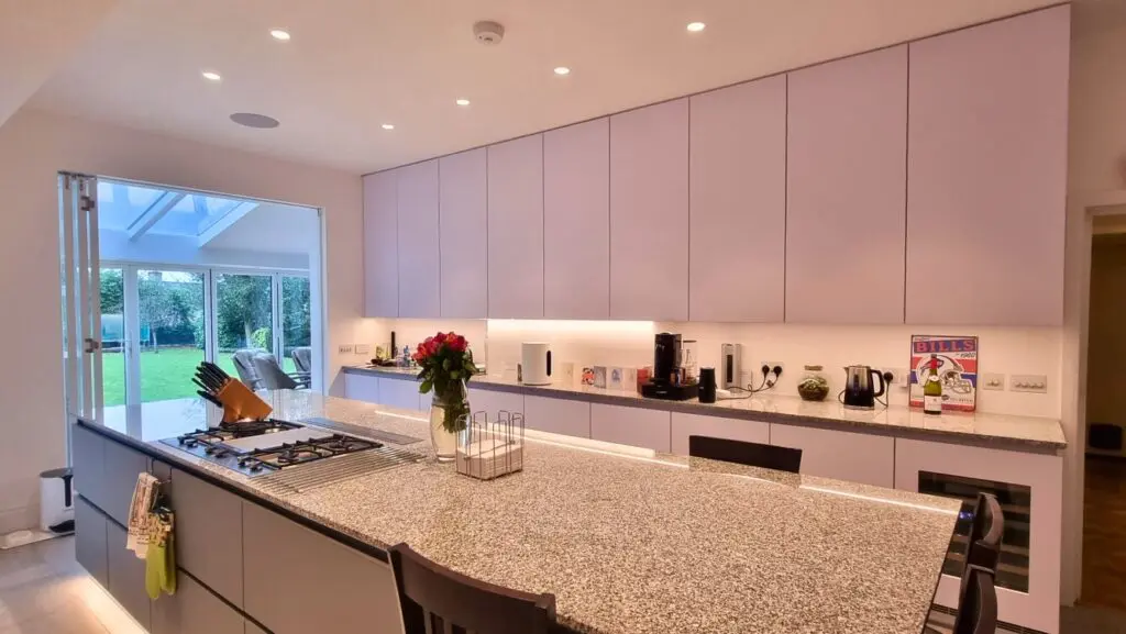 White FENIX wall cabinets above the granite worktop, with the island in the foreground.