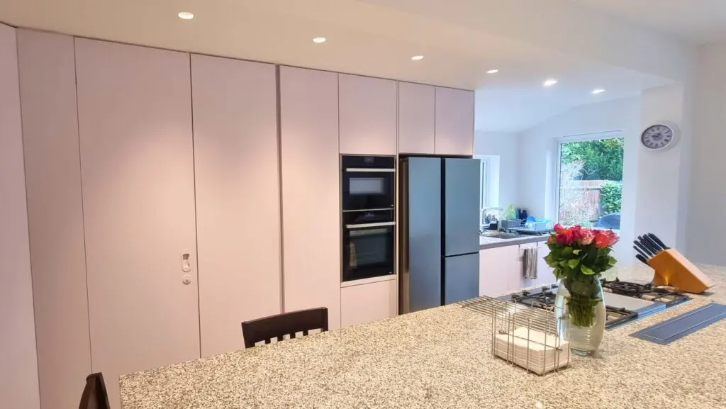 Tall white cabinetry around the oven stack and refrigerator.