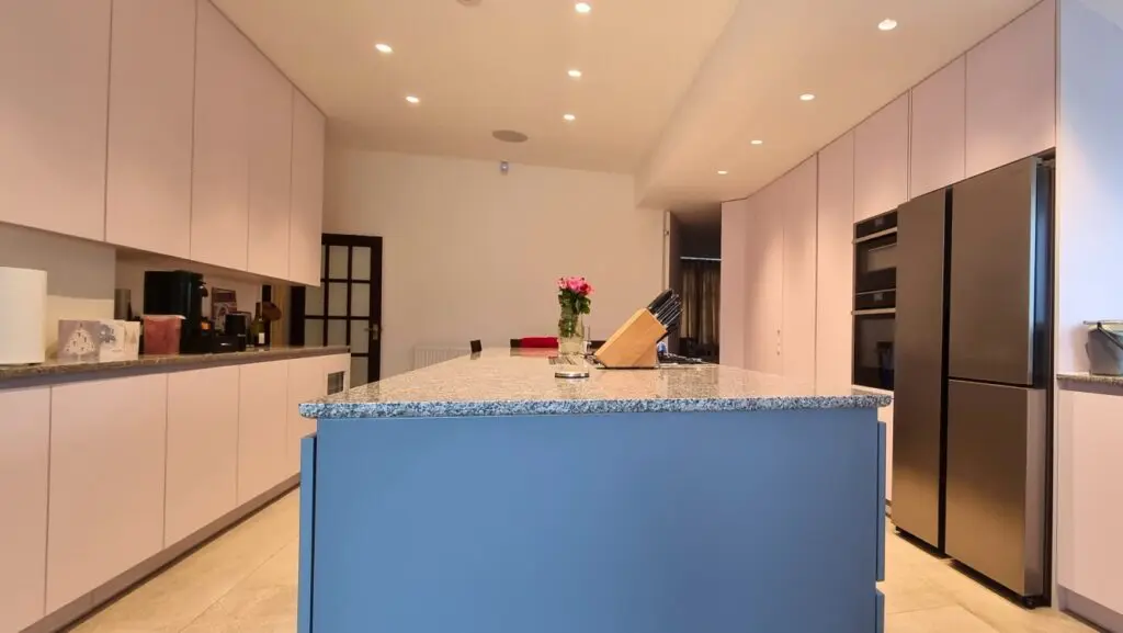 The large island between the two cabinet runs, with the refrigerator and built-in appliances alongside.
