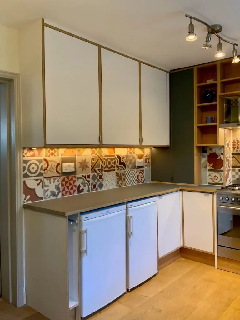 White wall cabinets, exposed timber edges and lighting above the preparation surface.