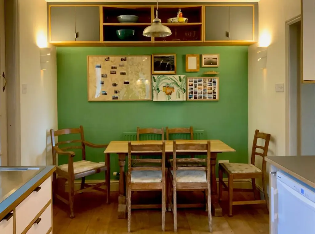 Closed cupboards and open shelving continue the kitchen materials above the dining table.