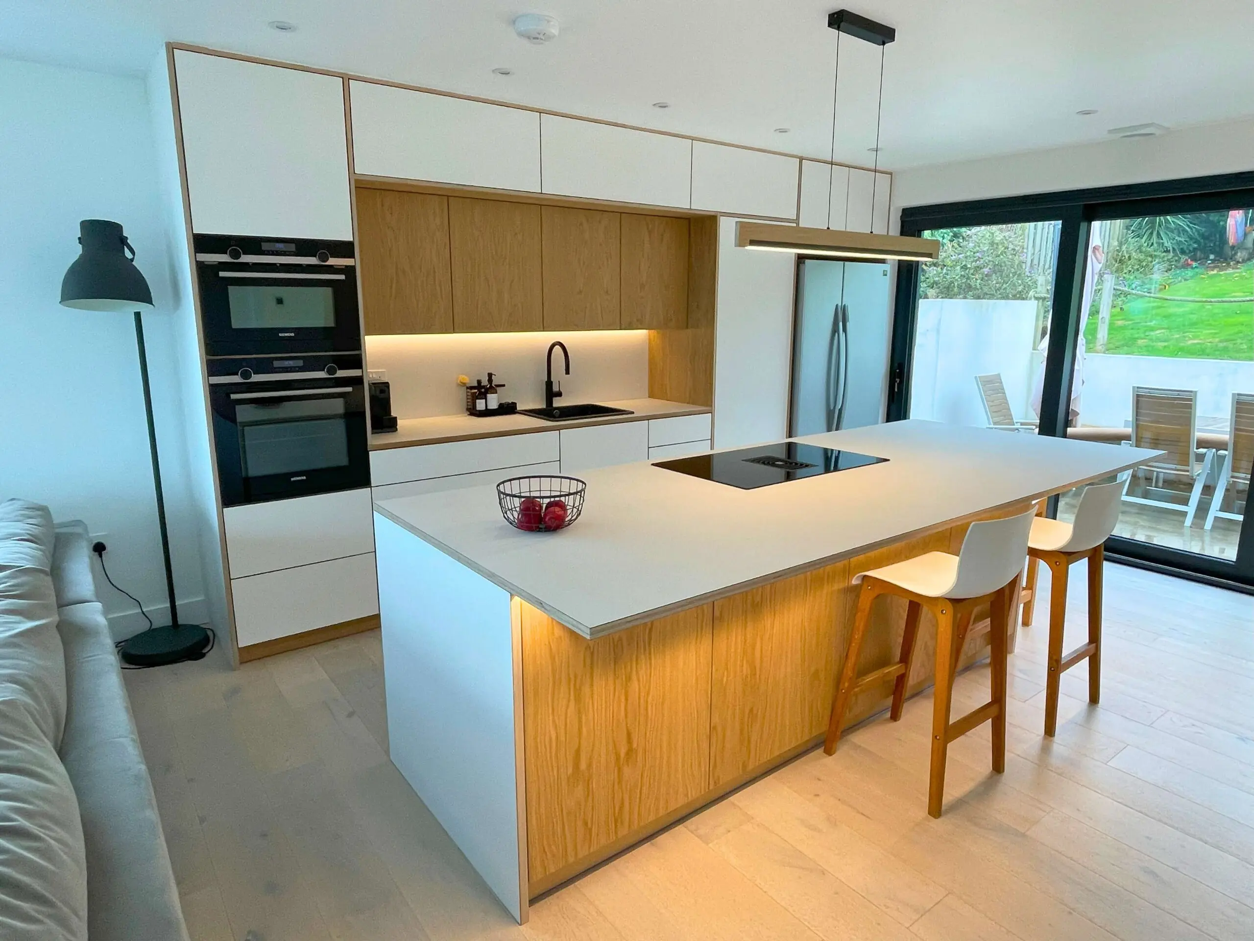 Scandinavian kitchen with island featuring oak veneer and white Fenix cabinets with seating area Bristol