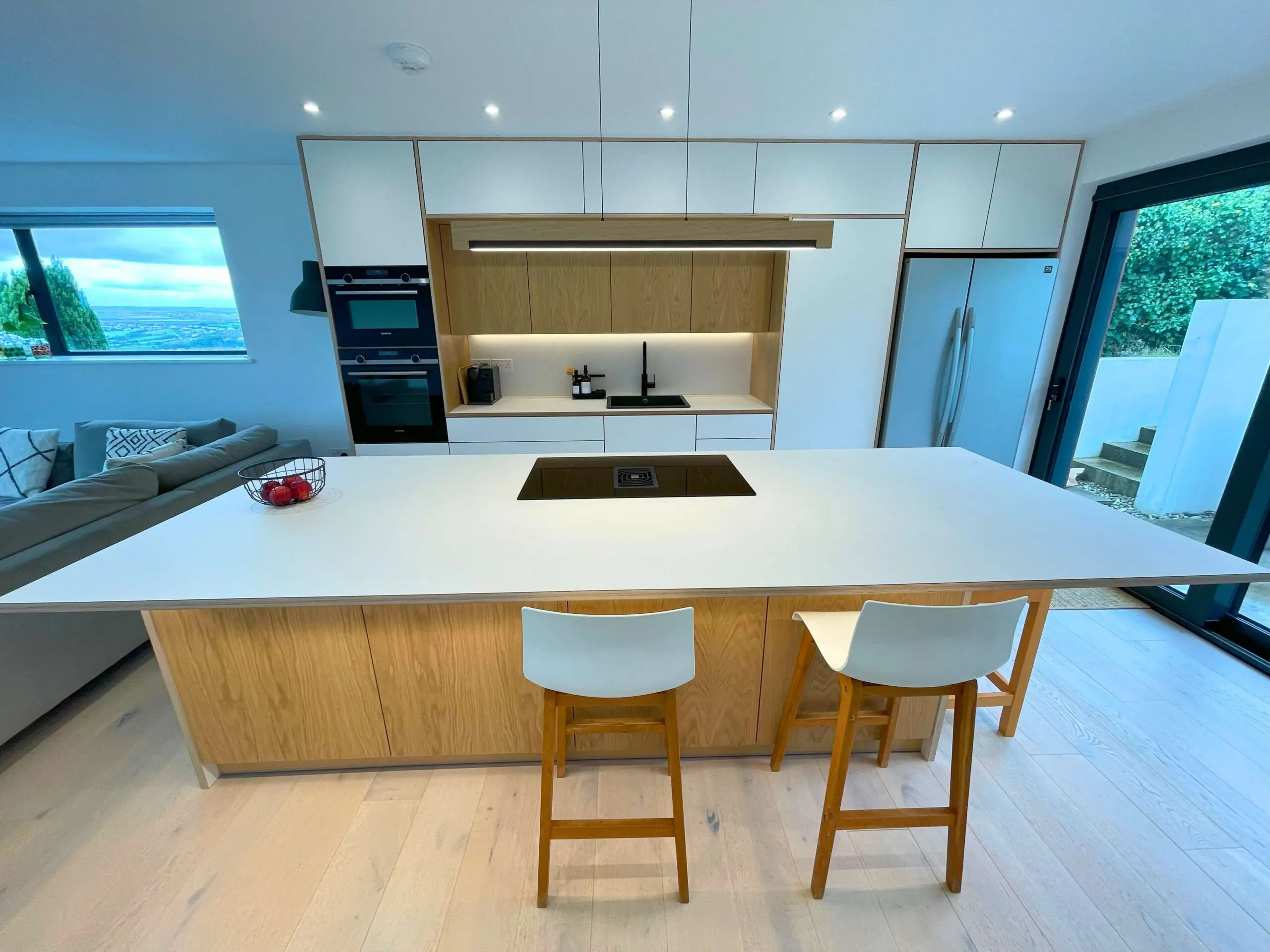 Bespoke kitchen island with oak veneer cladding in Scandinavian kitchen open-plan Bristol by JS DECO