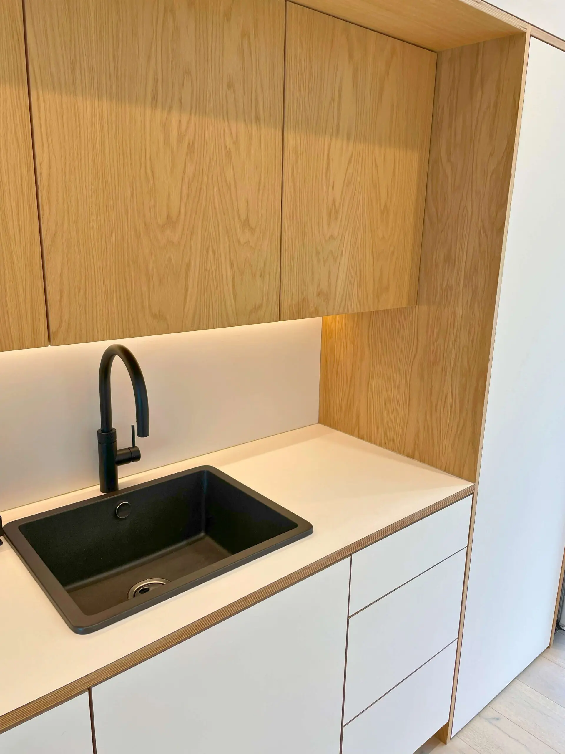 Scandinavian kitchen sink area with oak veneer cabinets and white handleless units Bristol by JS DECO