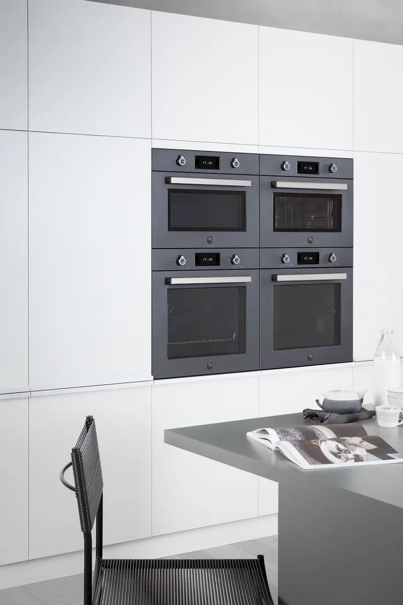 Four black Bertazzoni built-in ovens displayed together within white cabinetry