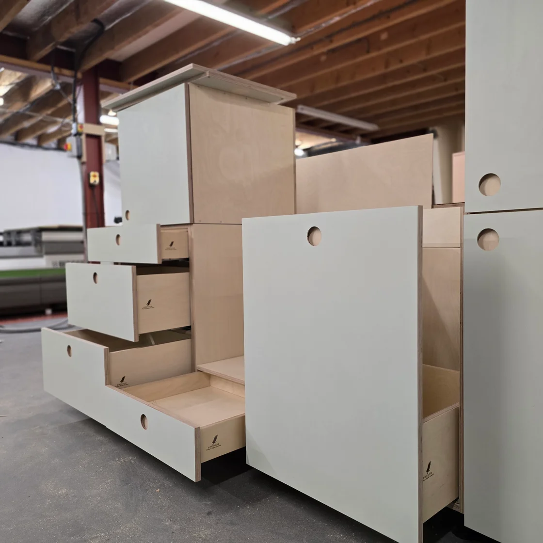 Plywood cabinetry with open drawers and circular finger pulls in the workshop.
