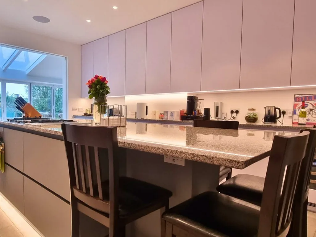 Contemporary bespoke kitchen with light cabinetry, breakfast bar and integrated lighting