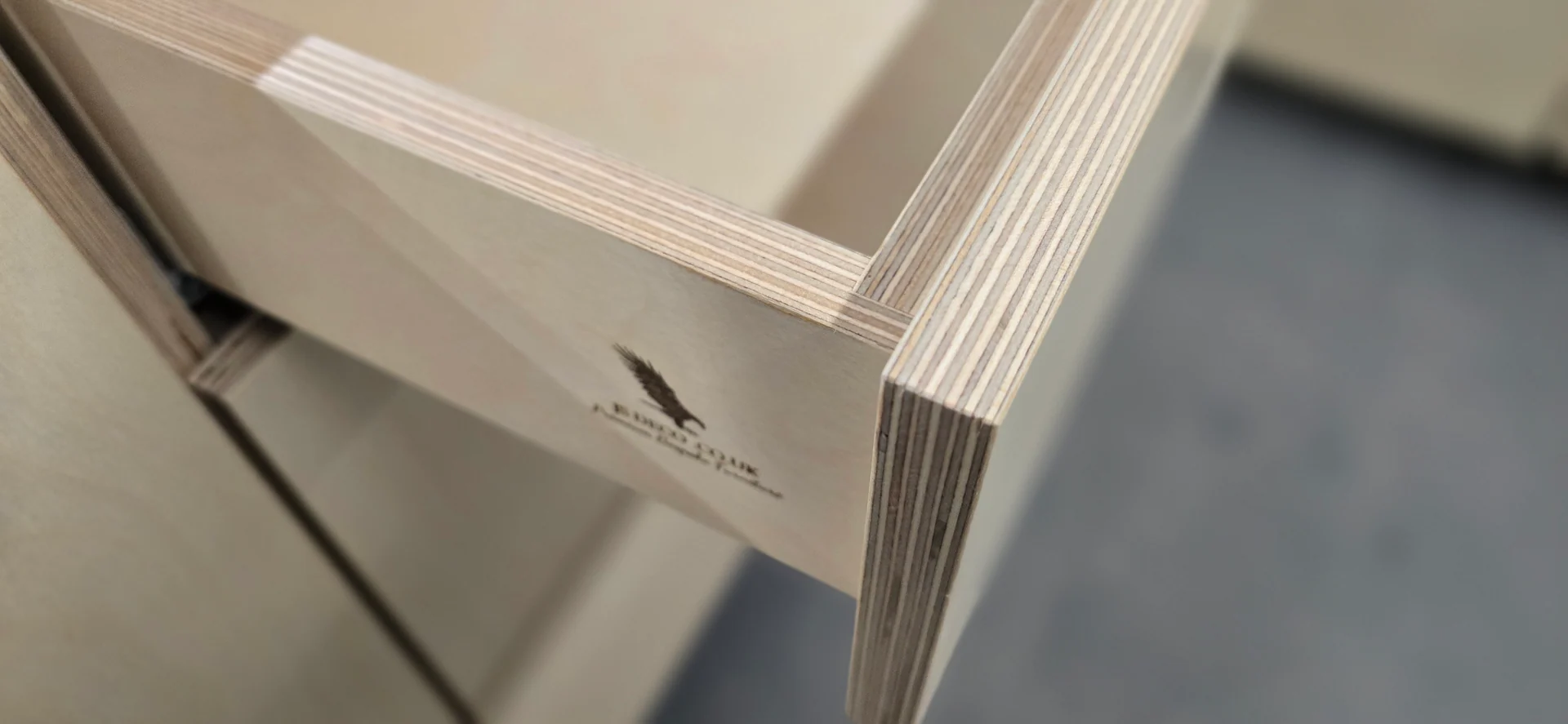 Close-up of a plywood drawer with exposed layered edges and the JS DECO workshop mark.