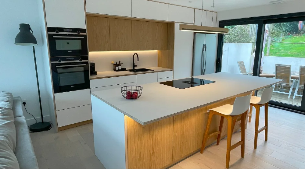 Plywood kitchen with white cabinetry, warm timber accents and a large island.