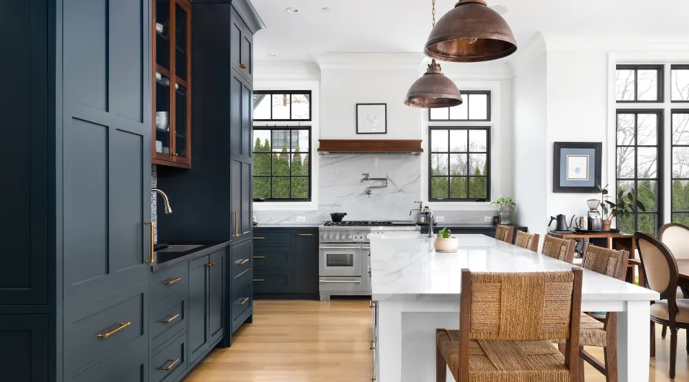 Deep blue painted Shaker kitchen with a white island and copper pendant lights.