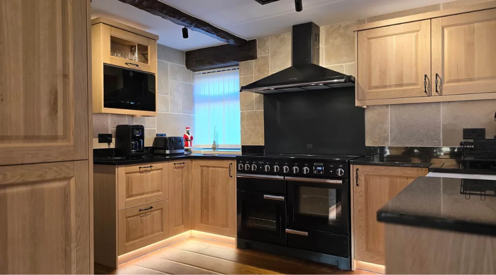 Traditional solid oak kitchen with black worktops and a black range cooker.