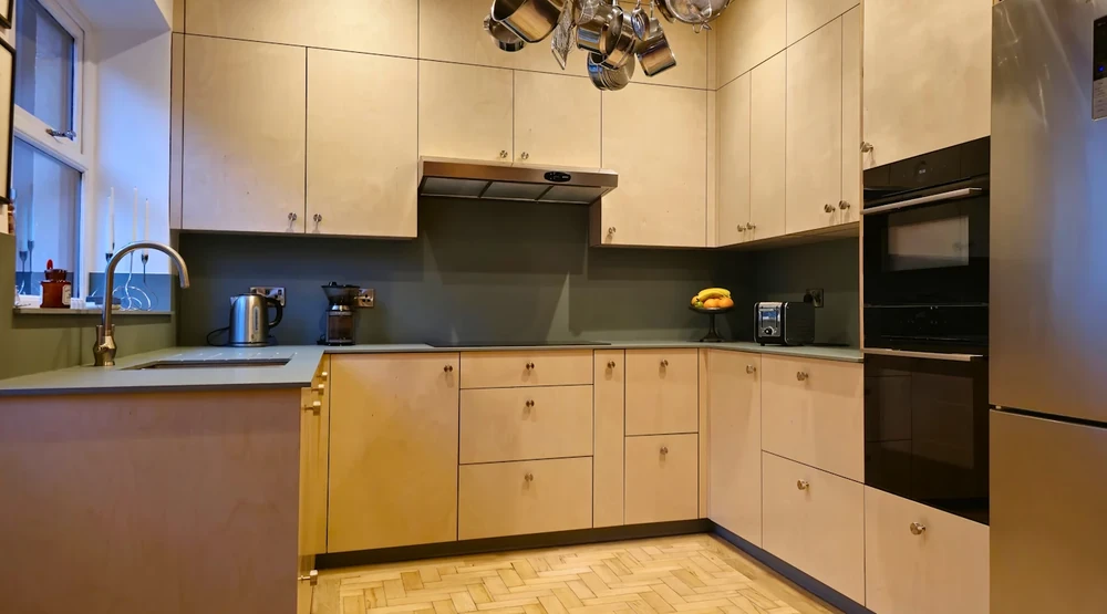 Natural plywood kitchen with matching cabinet doors, drawers and grey worktops.