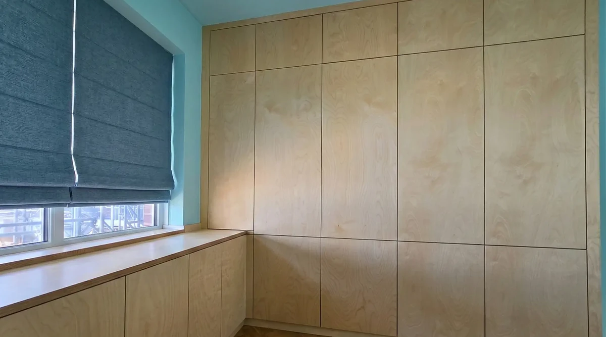 Bespoke birch plywood fitted wardrobes with matching storage beneath the window.