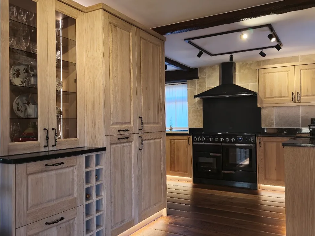 Traditional solid oak bespoke kitchen with illuminated cabinetry and black range cooker