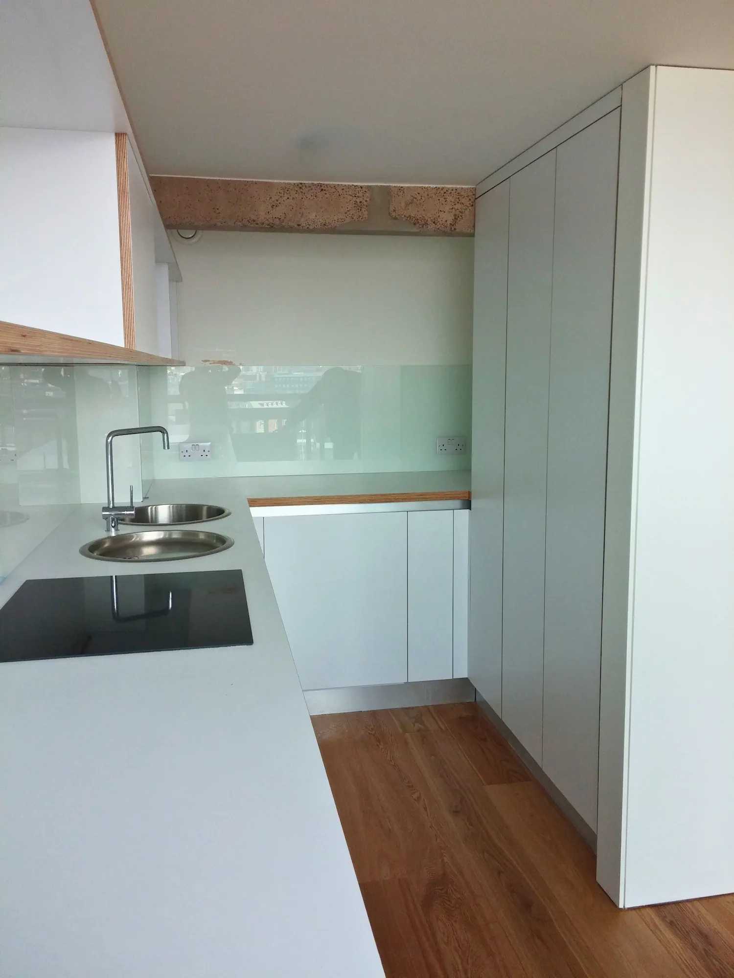 Modern industrial kitchen with white handleless tall units, plywood edge detail, and glass splashback in Park Hill Sheffield