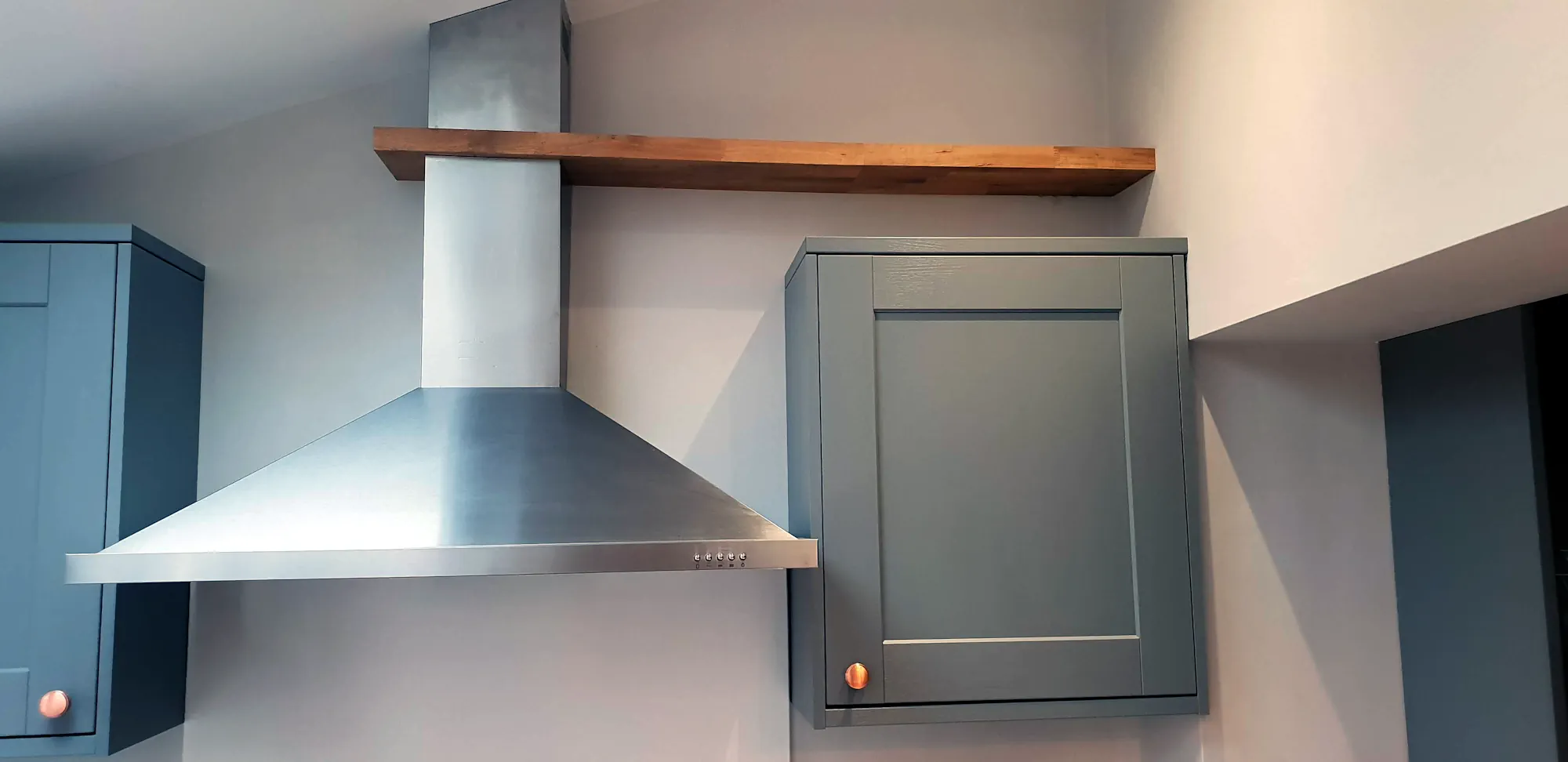 Combination of solid oak floating shelve and stainles steel extractor fan in the kitchen