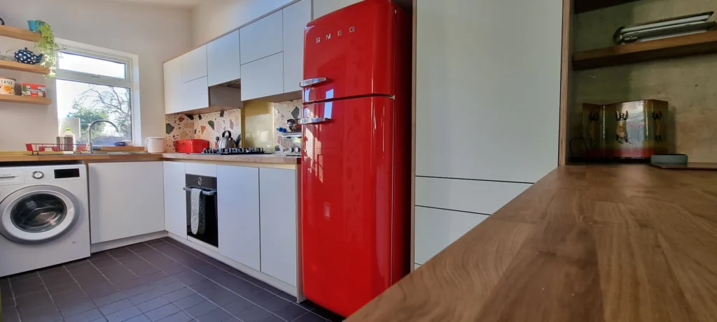 White FENIX fronts, solid oak worktops and a red Smeg fridge in the completed Leeds kitchen