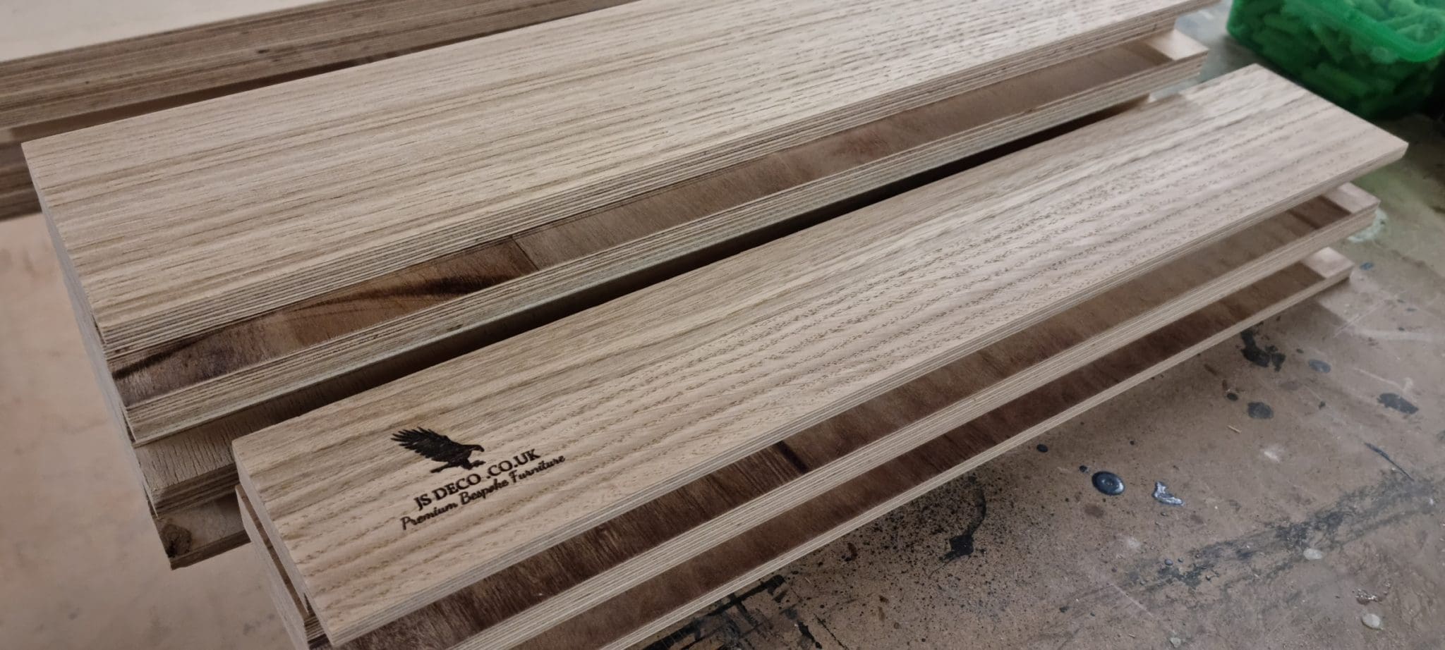Close-up of solid oak joinery detail with JS DECO branding on a fitted wardrobe drawer during manufacture.