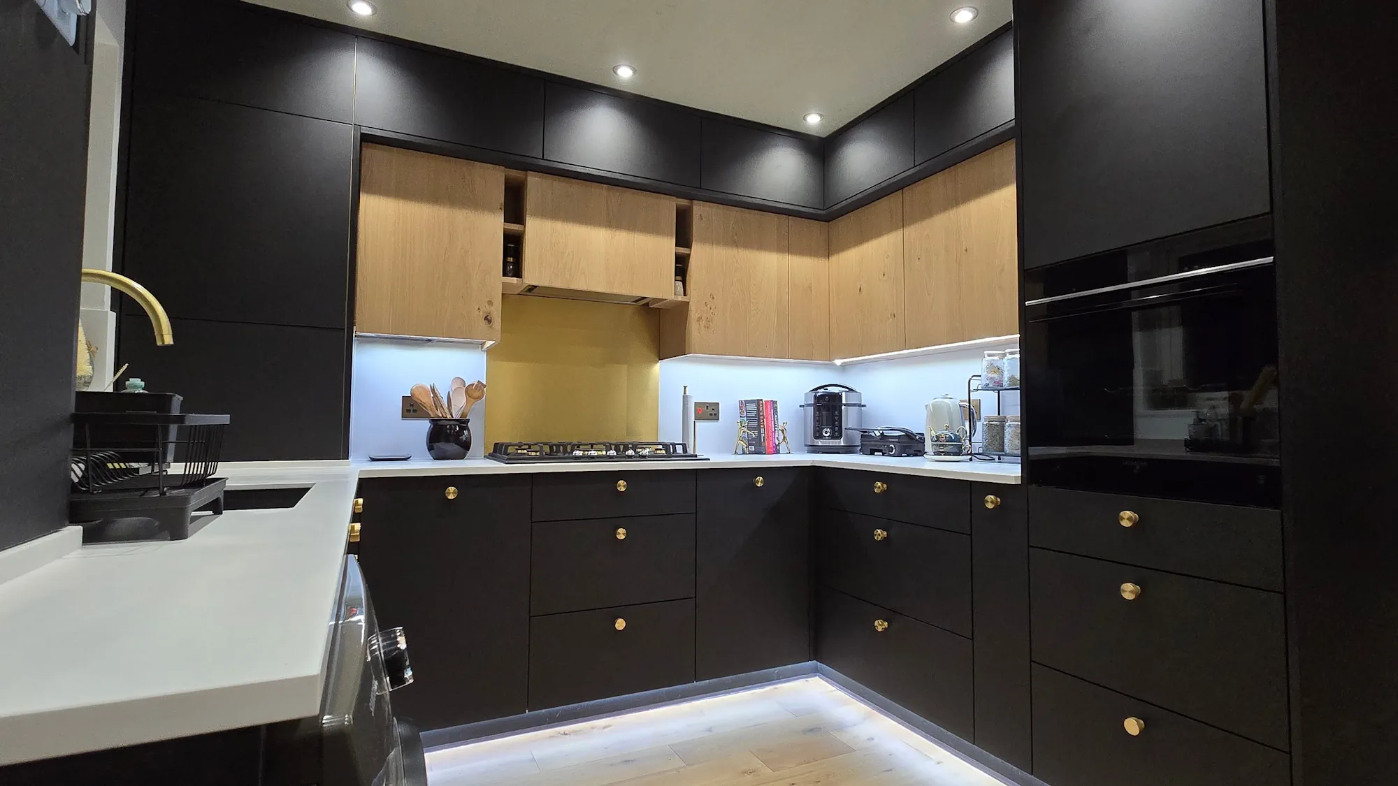 Detail of FENIX NTM Nero Ingo kitchen with oak veneer wall units and brushed brass splashback