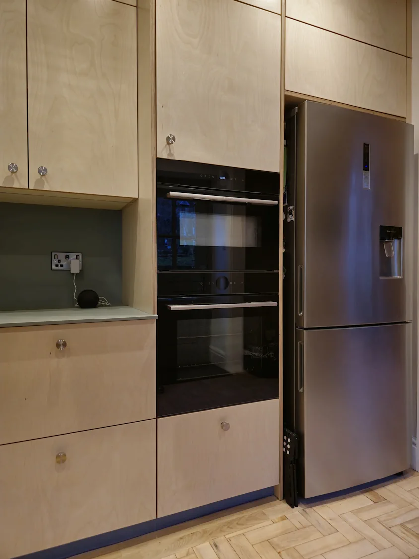 Tall plywood housing for Bosch Siemens ovens in Matlock Tall plywood cabinet housing double Bosch Siemens ovens and freestanding fridge freezer in Matlock bespoke kitchen