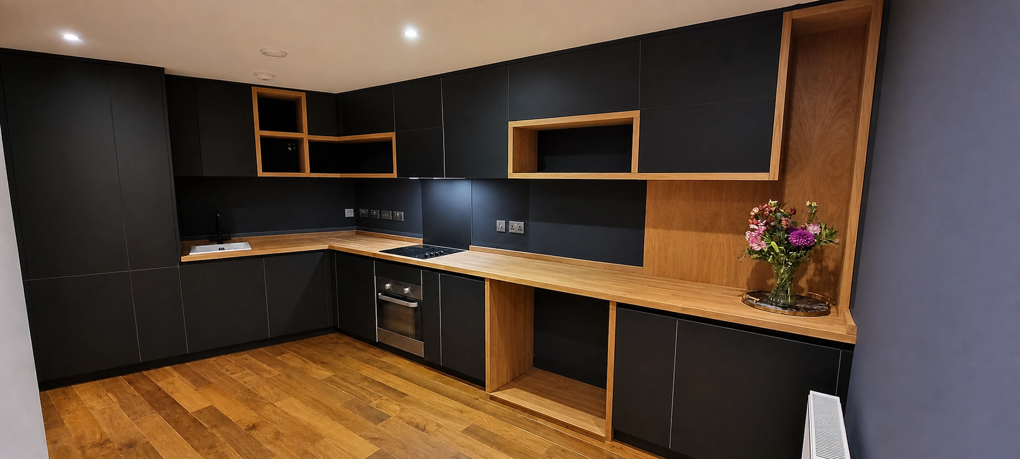 Completed Lambarde Square apartment kitchen Wide view of bespoke Lambarde Square apartment kitchen with FENIX Nero Ingo fronts and solid oak surfaces