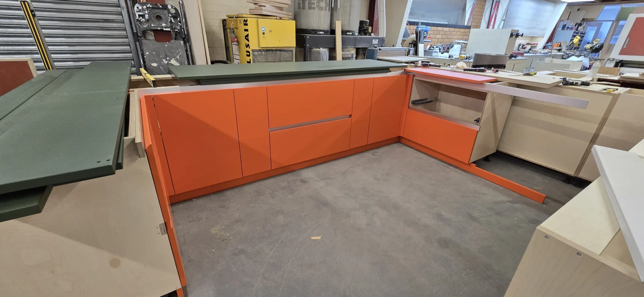Workshop assembly: the orange fronts and plywood cabinetry before installation.