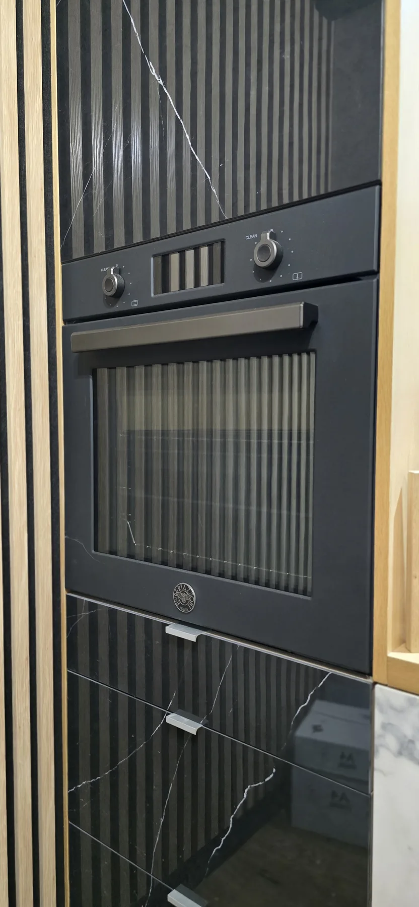A black Bertazzoni built-in oven set within JS DECO cabinetry