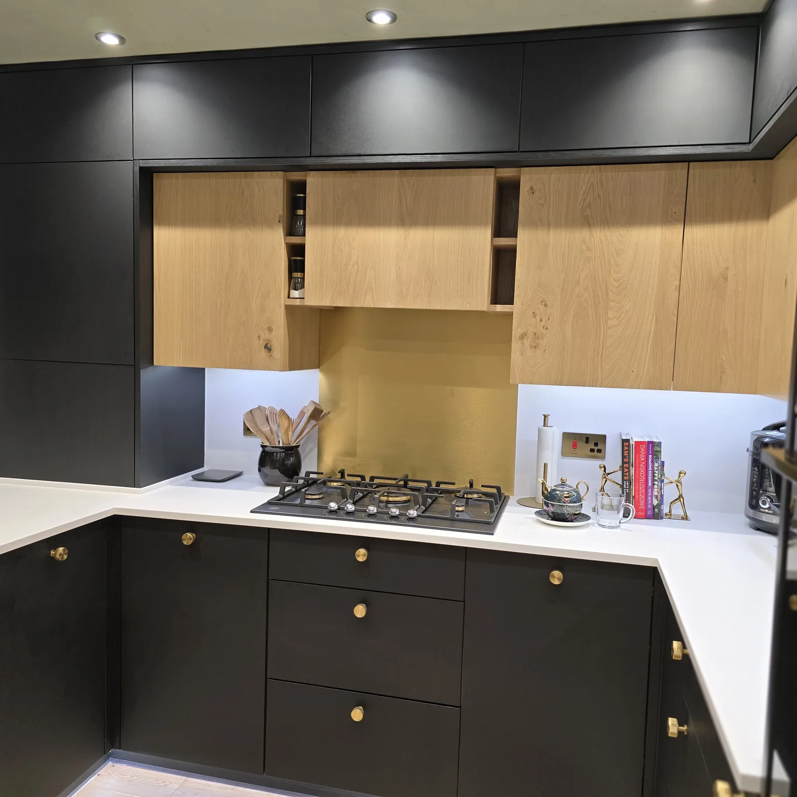 A JS DECO kitchen with dark cabinetry, timber wall cupboards and a gas hob