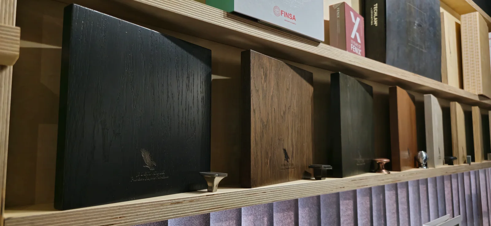 Timber door samples and cabinet handles displayed on plywood shelving in the JS DECO studio